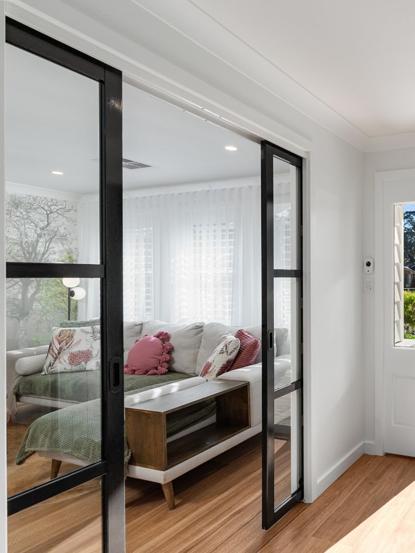 nterior view of the Bundanoon full home renovation and extension by a Southern Highlands builder, featuring black steel sliding doors, timber flooring and a light-filled living room.