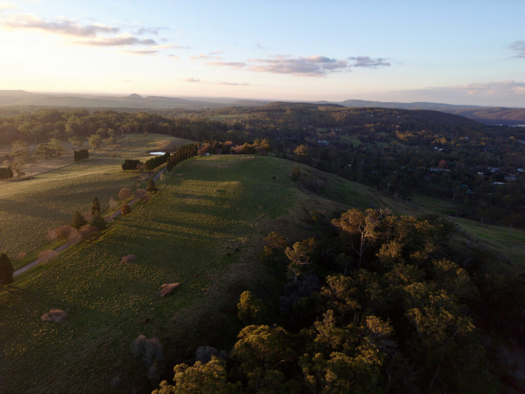 Aerial view of rolling hills and farmland at sunset in the Southern Highlands, captured by Southern Highlands builder Precision Build NSW.